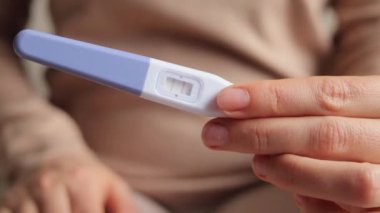 Yeni hayat, kadın sağlığı, mutlu değişiklikler ve döllenme. İki kırmızı çizgili pozitif hamilelik testi tutan kimliği belirsiz kadın hamile olduğunu doğruladı..