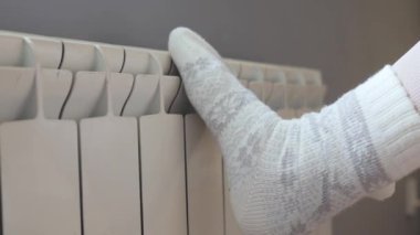 Soğuk evde ısınmaya çalışan, elektrikli pille bacakları tutan, sıcak çorap giyen, merkezi ısıtmada sorun yaşayan, tanınmamış bir kadın..