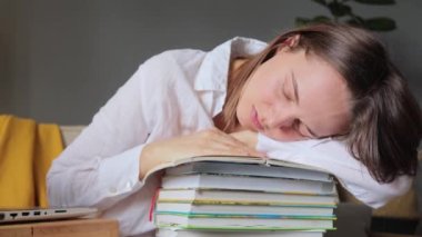 Bir sürü kitabı olan genç bayan öğrenci uzun saatler sonra yorgun hissediyor. İç kısımda kitap yığınının üzerinde uyuyor. Sınav için hazırlanırken uykuya dalıyor..