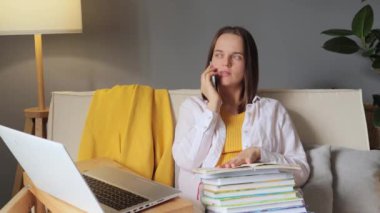 Çekici, çalışkan, akıllı bir kadın evde oturmuş ev kıyafetleri içinde öğretmenle eğitim hakkında sohbet ederken akıllı bir telefonla konuşuyor..