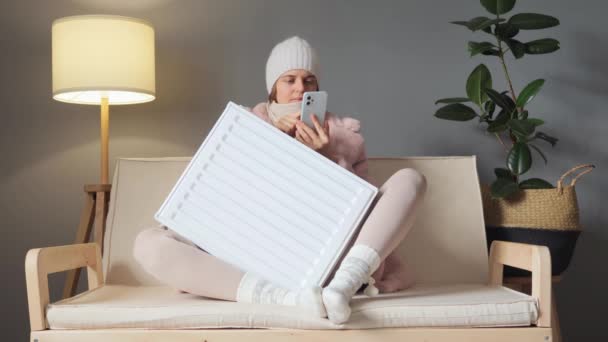 Şapka Kışlık Palto Giymiş Şaşkın Bir Kadın Evde Koltukta Oturup — Stok video