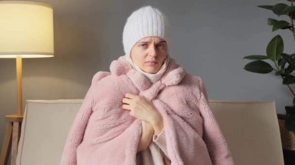 暖かいコートを着てイオン冷たい家に座っている病気の女性と暖房の問題で部屋に座っている間にインフルエンザの症状を抱える熱咳の欠如に苦しむ帽子 — ストック動画