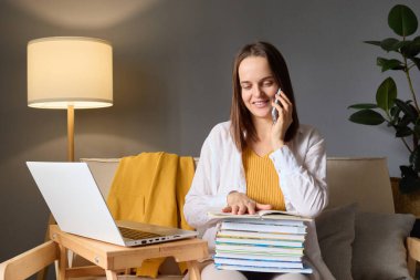 Eğlenceli, çalışkan bir kadın evde akıllı bir telefonla konuşuyor. Üniversite için ödev yapıyor. Özel hocayla tatilde konuşuyor..