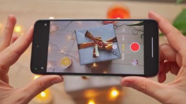 Bayram için hazırlanmış güzel bir hazırlık kutusunun görüntüsünü alan veya kaydeden kadın elleri görüntüsü akıllı telefon tutarak neşeli içerik oluşturur.