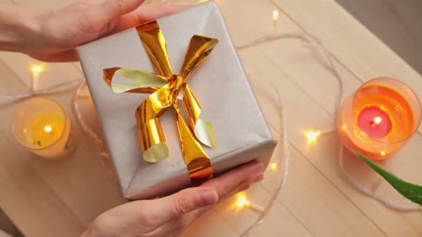 ホリデーシーズン中 大晦日または冬の誕生日未確認の女性は クリスマスのお祝い プレゼントを包むために準備する彼女の手に黄金の弓で素敵なギフトボックスを保持しています — ストック動画