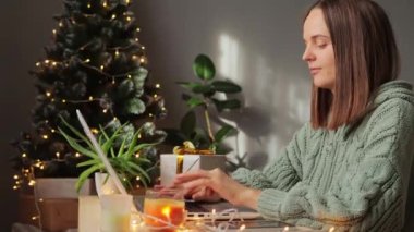 Noel zamanı. Ev bilgisayarında çalışan bir kadın, arka planda yılbaşı ağacıyla çalışıyor, klavyede daktilo yazıyor, uzaktan yaptığı işi not alıyor..