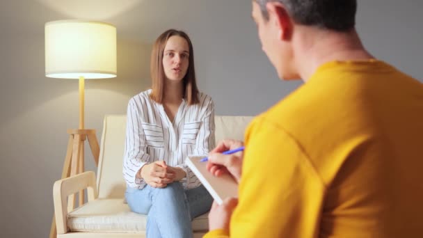 信任的顾问 精神疾病顾问 女性患者和心理健康专业人员在舒适的沙发上进行真诚的交谈 讨论感情和寻找解决方案 — 图库视频影像