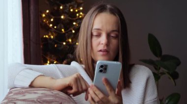 Samimi bir Noel geçmişi. Cep telefonunda mesaj çeken bir kadın. Uykumda geziniyorum. Oturma odasında kanepede oturup esnerken cep telefonu kullanmaktan sıkılmış genç bir kadın..