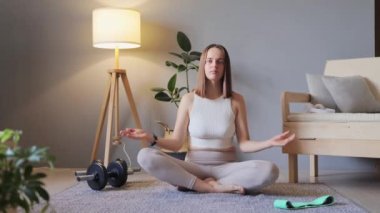 Sakin ve kendinden emin bir kadın. Sağlık için spor rutini. Lotus pozisyonunda güzel bir atlet. Huzurlu bir zihin ve vücut. Evde yerde otururken yoga yapan çekici bir kadın..