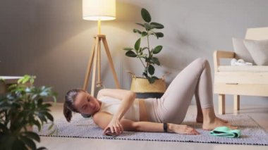 Modern aletler kullanan atletik bir kadın vücut gücü için statik egzersiz yapıyor ve oturma odasında fiziksel egzersiz yapıyor..