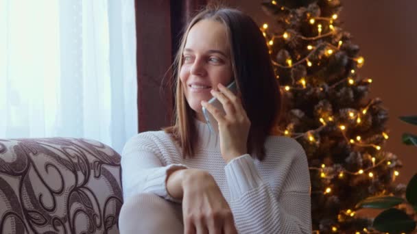 一位快乐而美丽的女士坐在客厅的沙发上 与朋友或家人进行非正式的电话交谈 讨论一些远距离的交流 — 图库视频影像