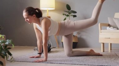 Body shaping and glutes workout. Fit woman in sportswear doing donkey kicks exercise with leg raise on floor, training butt and hamstring workouts and fitness routines.