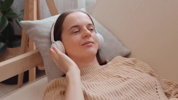 Красива Жінка Трикотажному Светрі Слухає Музику Навушниками Дивані Вдома Насолоджуючись — стокове відео