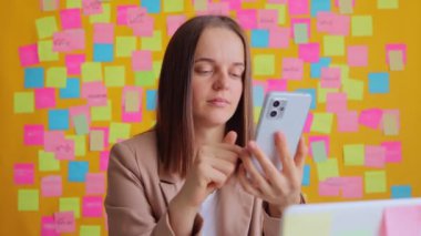 Ofiste bilgisayarla duvara karşı poz verirken sosyal ağda facepalm hareketi yaparken önemli bir şeyi hatırlayan üzgün iş kadını akıllı telefon kullanıyor..