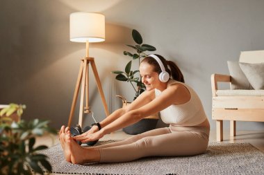 Sağlıklı ve zinde bir kadın egzersiz yapıyor. Kablosuz kulaklıkla müzik dinliyor. Vücut aerobiği eğitimi alıyor..