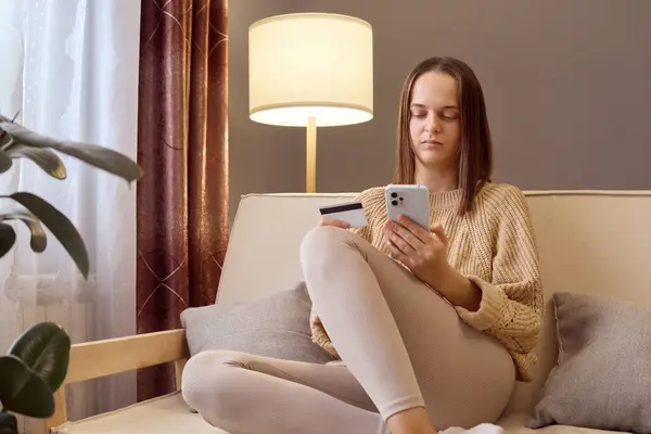 Concentrated female bank customer using phone to make easy secure payments online in convenient app spending bonus cashback received on credit card for internet paying.