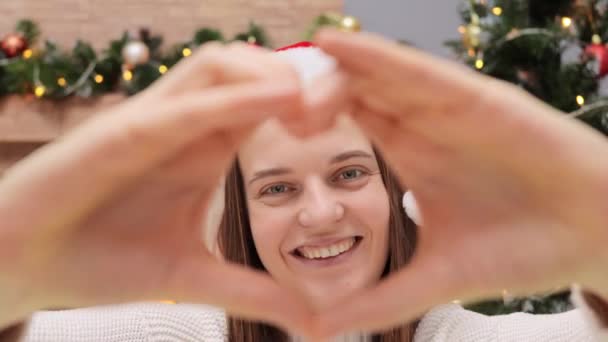 Pozytywna Radosna Zadowolona Kobieta Kapeluszu Świętego Mikołaja Patrząc Przez Serce — Wideo stockowe