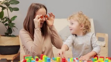 Gelişimsel oyuncaklar. Bebek yaratıcılığı. Şekil ayırıcı. Duygusal zeka. Beyaz bir kadın, bebeğiyle evde oynuyordu. Gözleri yuvarlak detaylarla kaplıydı..