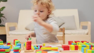 Duyusal oyun. Renkli ahşap blok yığını. Bebek dostu bir öğrenme. Duygusal dayanıklılık oyunları. Oyun odasındaki masada tahta şekilli bir oyuncakla oynayan küçük kız..