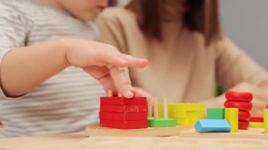 Basit gelişim oyuncakları. Oynayarak öğreniyorum. Yığınla eğlence. Bebek dostu aktiviteler. Tanınmayan anne, yeni yürümeye başlayan kızıyla iç mekanda oynuyor..
