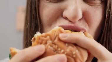 Burger yiyen, ağzında keskin bir ağrı hisseden, dilini ya da yanağını ısıran, mide iltihabı ve diş problemi olan, ya da çenesinde eklem hastalığı olan, tanınmayan kahverengi saçlı kadının yakın çekimi..