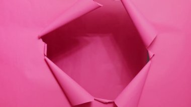 Aşırı neşeli, kahverengi saçlı, şık kazak giyen, pembe arka plandaki yırtık delikte dikilen, mutlu, heyecanlı ve inanılmaz bir mutluluğu ifade eden bir kadın..