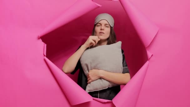 Sömnig Kvinna Bär Sovmask Och Pyjamas Poserar Pappershål Rosa Vägg — Stockvideo