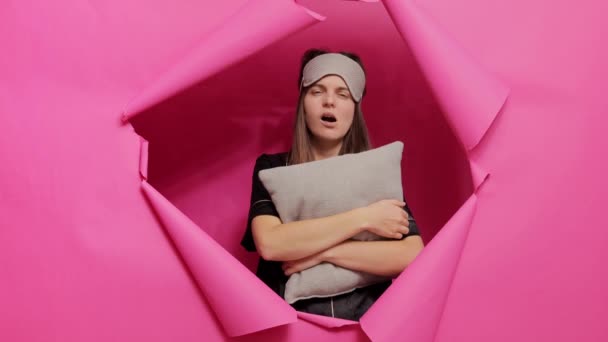 Уставшая Усталости Женщина Маске Пижаме Позирует Бумажном Отверстии Розовой Стены — стоковое видео