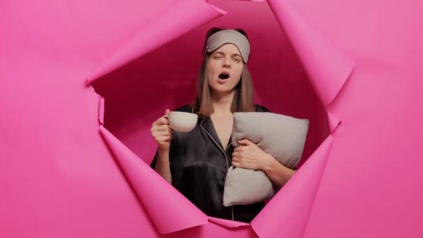 Сумна Жінка Сплячій Масці Піжамі Позує Паперовому Отворі Рожевої Стіни — стокове відео