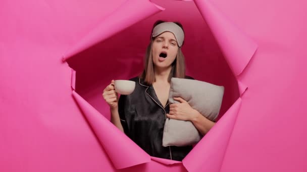 Несчастная Женщина Маске Пижаме Позирующая Бумажном Отверстии Розовой Стены Подушкой — стоковое видео