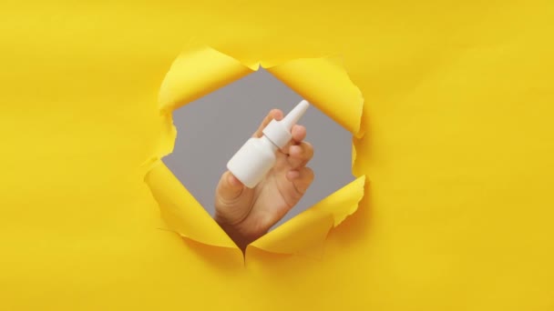 流感治疗药物 疾病药物的选择 疾病治疗喷剂 过敏反应护理 无法辨认的人的手 显示鼻腔喷出破洞黄色休闲纸 — 图库视频影像