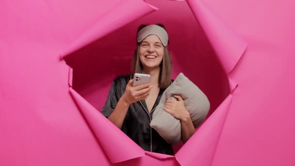 Glädjande Kvinna Bär Sovmask Och Pyjamas Med Mobiltelefon Läser Roliga — Stockvideo