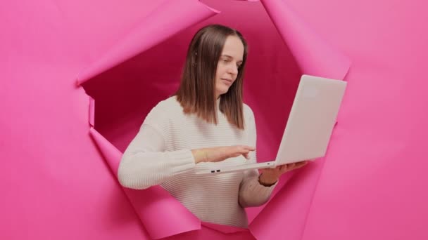 Internetová Technologie Překvapená Dospělá Hnědovlasá Žena Držící Notebook Prorážející Růžovou — Stock video
