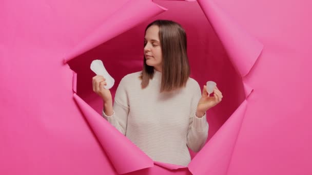 Niepewna Radosna Kobieta Trzymająca Kubek Menstruacyjny Serwetkę Higieniczną Wybierając Artykuły — Wideo stockowe