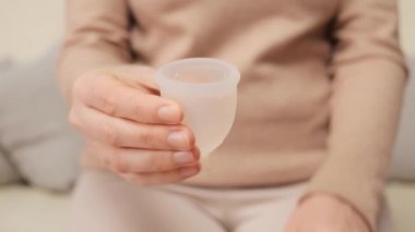 Özel ve güvenli bir adet tedavisi. Sıfır atık jinekoloji. Sıvı üreme sağlığı. Silikon ve lastik bakım. Evin içinde aybaşı fincanı tutan tanınmayan bir kadın.