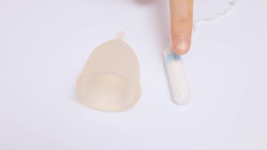 Adet bardağı ve beyaz arka planda izole edilmiş kadın hijyen tamponu. Kadın hijyen ürünlerini işaret ediyor. Reklam için yer var.