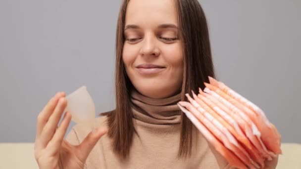 Uśmiechnięta Kobieta Brązowymi Włosami Trzymająca Ochraniacze Higieniczne Kubki Menstruacyjne Podejmująca — Wideo stockowe