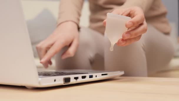 Nieznana Kobieta Korzystająca Laptopa Trzymając Kubek Menstruacyjny Przez Laptopa Badając — Wideo stockowe