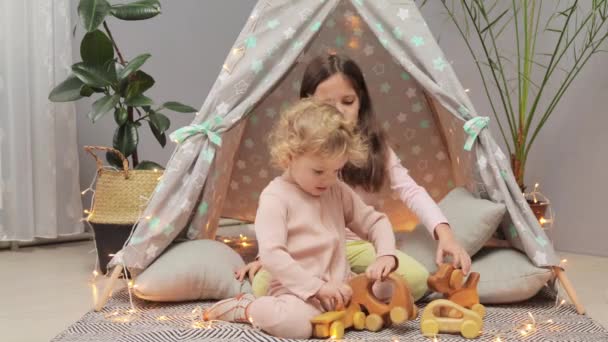 행복한 아이들이 거실에서 보호소에서 놀라운 분위기를 즐기는 장난감과 여동생과 Wigwam — 비디오