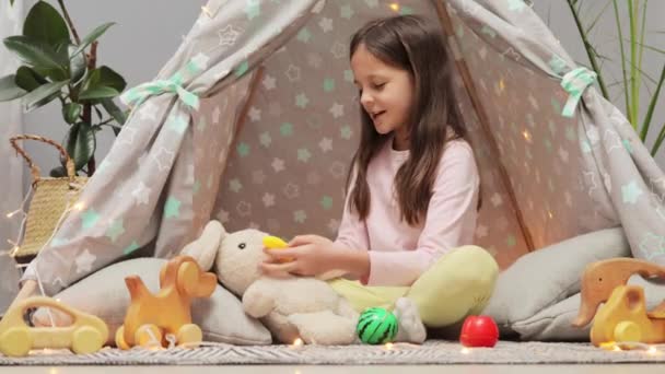 Gülümseyen Kahverengi Saçlı Küçük Kız Oturma Odasındaki Çadırda Oturmuş Oyuncak — Stok video
