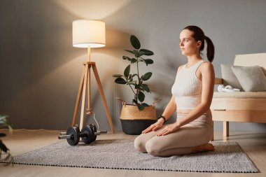 Fitness ve yoga eğitimi. Vücut için kapalı alanda eğitim. Güzel kadın egzersizi. Spor salonunda oturan güzel bir kadın yoga kıyafetleri ve taytlar üzerinde çalışıyor.