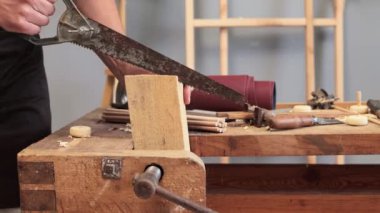 Kereste ustalığı. Zanaatkar iş başında. Ahşap yaratıcı stüdyo alanında kesinlik. Tanımlanamayan marangoz atölyesinde el testeresiyle kumsuz bir tahta parçası kesiyor.