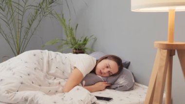Akıllı telefonlu sıkılmış genç bir kadın evde evde yatıp mesaj ya da telefon bekliyor mutsuz, sıkıcı ve sıkıcı bir hafta sonu sabahı geçiriyor.