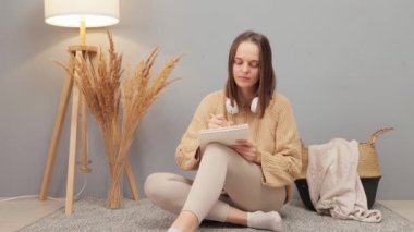 Not defterine siyah saçlı, ciddi şekilde konsantre olmuş güzel bir kadının hafta sonları evde bej rengi süveter giyip ev içinde poz vermek gibi bir sürü planı var.