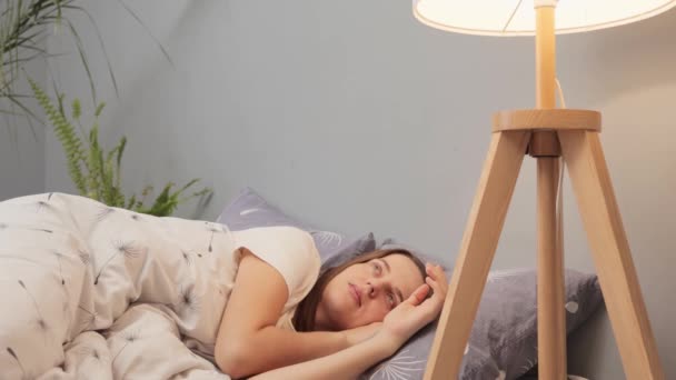 今天晚上 躺在床上躺着的白人女人 靠着手掌 关掉床边的灯睡觉 需要休息 在卧室里享受睡午觉的乐趣 — 图库视频影像