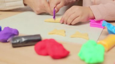 Evde aile yaratıcılığı. Yumuşak ve renkli bir eğlence. Anaokulu el işi seansı. Tanımlanamayan kız ve anne evin içinde renkli kil plastikçiliği oynuyorlar.