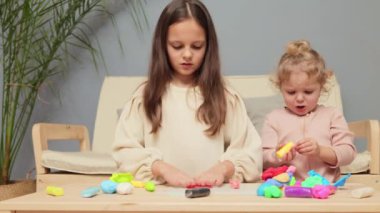 Kardeş heykeli eğlencesi. Çocuk dostu zanaat zamanı. Renkli plastiklerle öğreniyorum. Kapalı alanda heykel yapma etkinliği. Evde plastik kalıplarla oynayan iki küçük kız kardeş.