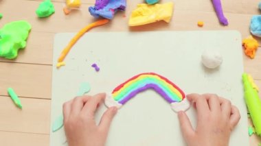 Bebekler için el işi eğlencesi. Renklerin eğlenceli keşfi. Eğitici oyun zamanı mutluluğu. Yaratıcı kalıp maceraları. Renkli plastik parçalarla oynayan tanınmayan küçük bir kız gökkuşağı yapıyor.