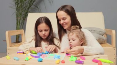 Yaratıcı el işi. Aile, yaratıcılık ve zanaat. Gülümseyen anne ve küçük kızlar evde kilden ya da plastikten modellik yapıyorlar. Birlikte yaratıcı zamanların tadını çıkarıyorlar.