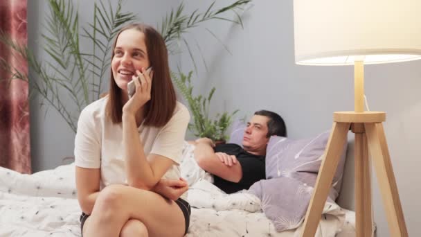 Sonriente Mujer Alegre Sentada Dormitorio Hablando Teléfono Móvil Chismorreando Con — Vídeo de stock